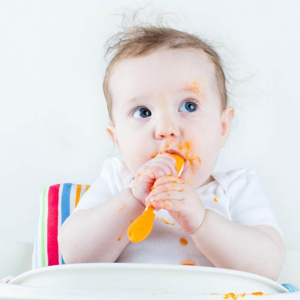 Baby in Highchair Chewing Spoon