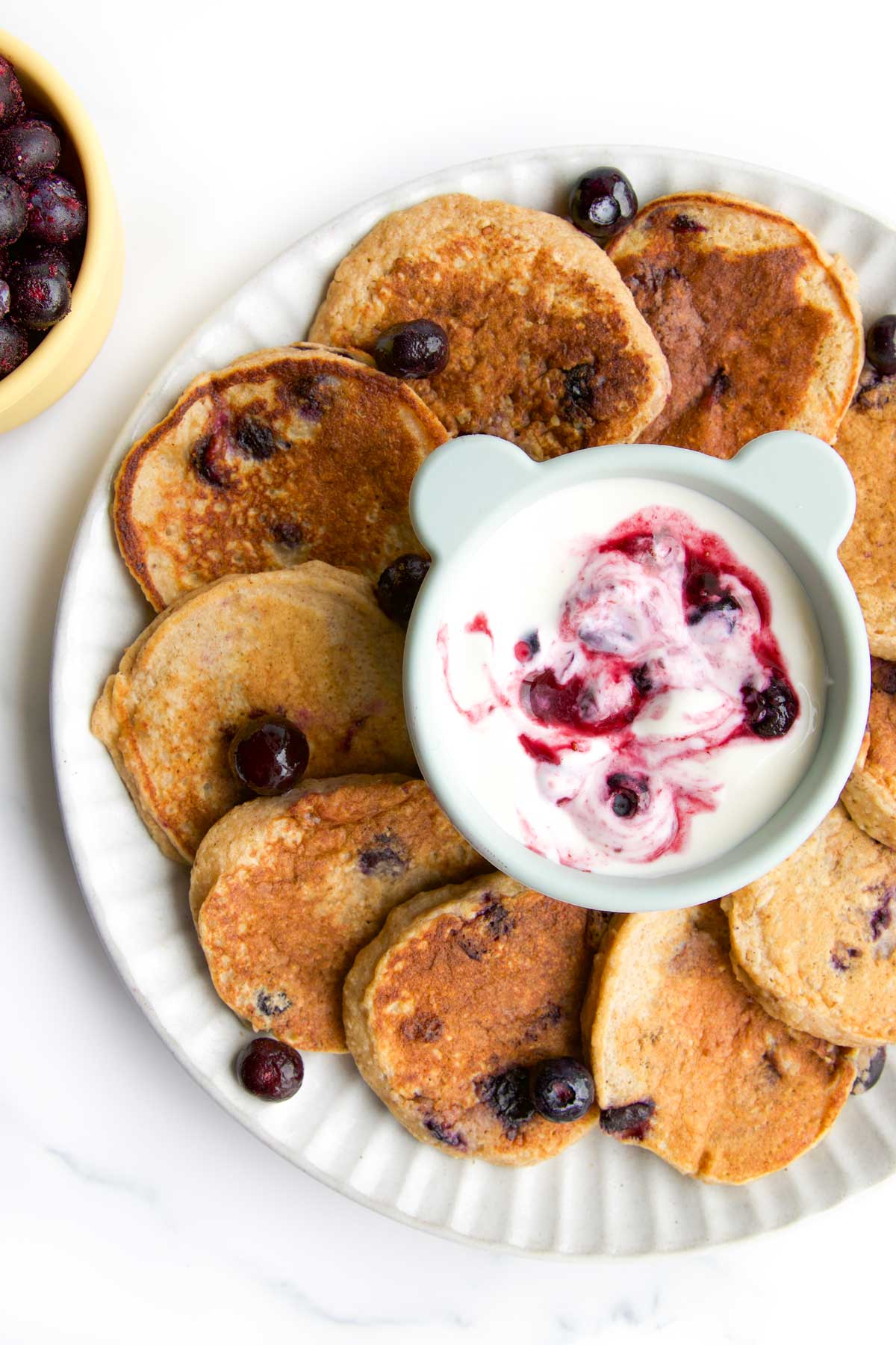 Close up Shot of Baby Blueberry Pancakes on Plate with Yogurt Dip in Centre. 