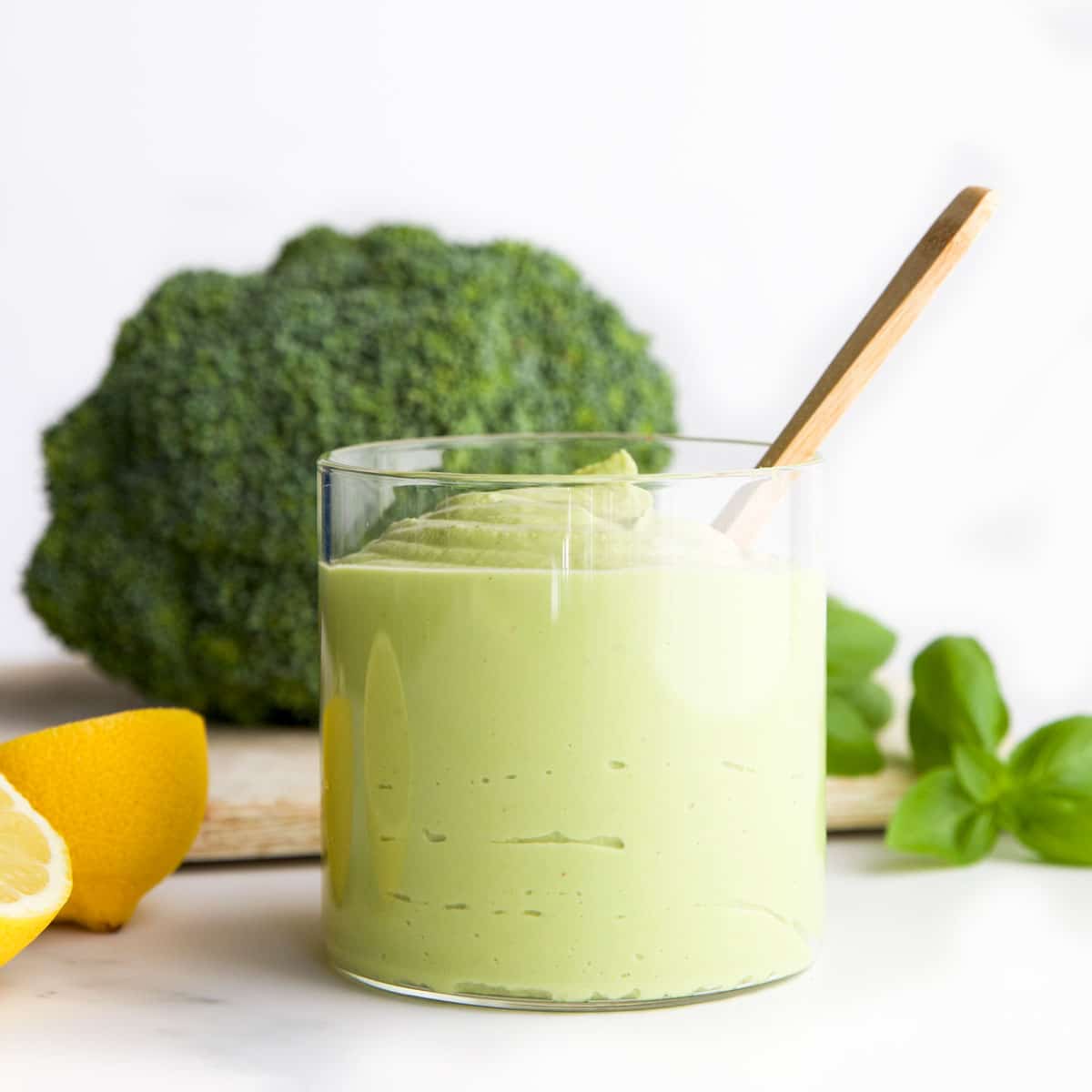 Creamy Broccoli Pesto in Jar with Broccoli Pesto Ingredients in Background. 