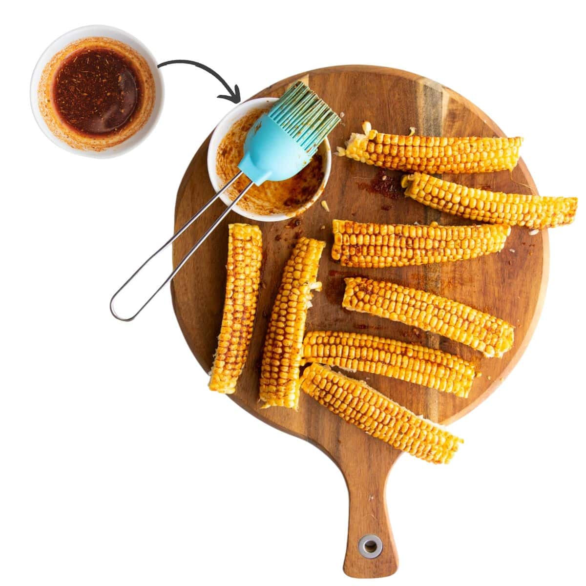 Wooden Chopping Board With Raw Corn Ribs Brushed with Seasoning. Bowl of Seasoned Oil and Pastry Brush to the Side.