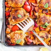 Top Down View of Cooked Chicken Chorizo Tray Bake in Tray with Fish Slice Removing a Chicken Thigh