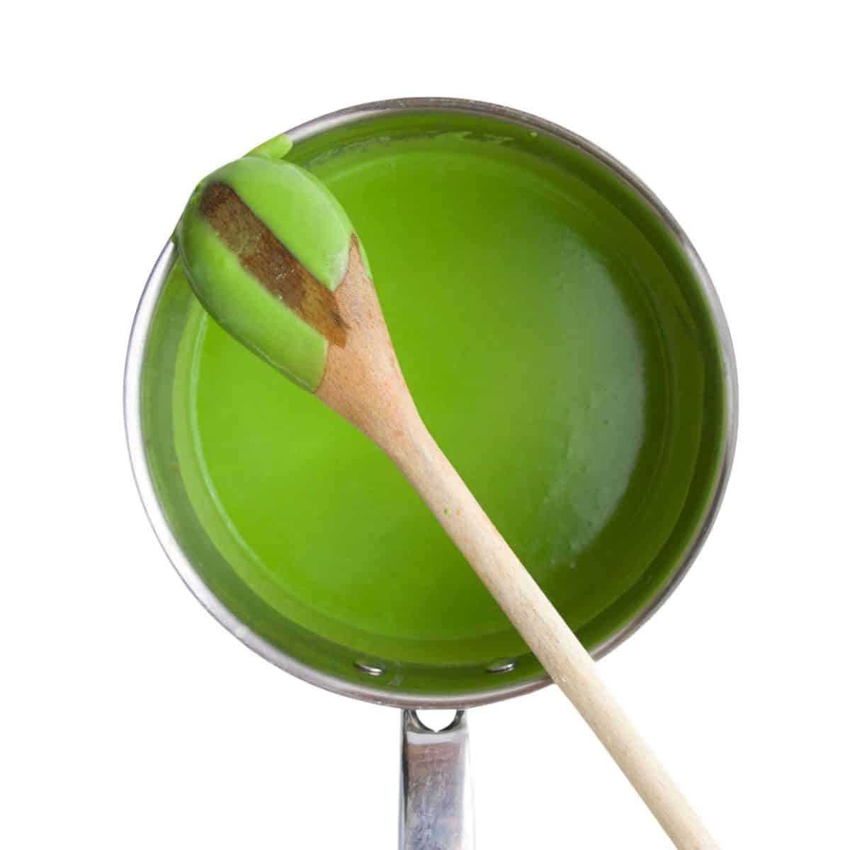 Green Sauce With Wooden Spoon on Top Showing Consistency of Sauce.