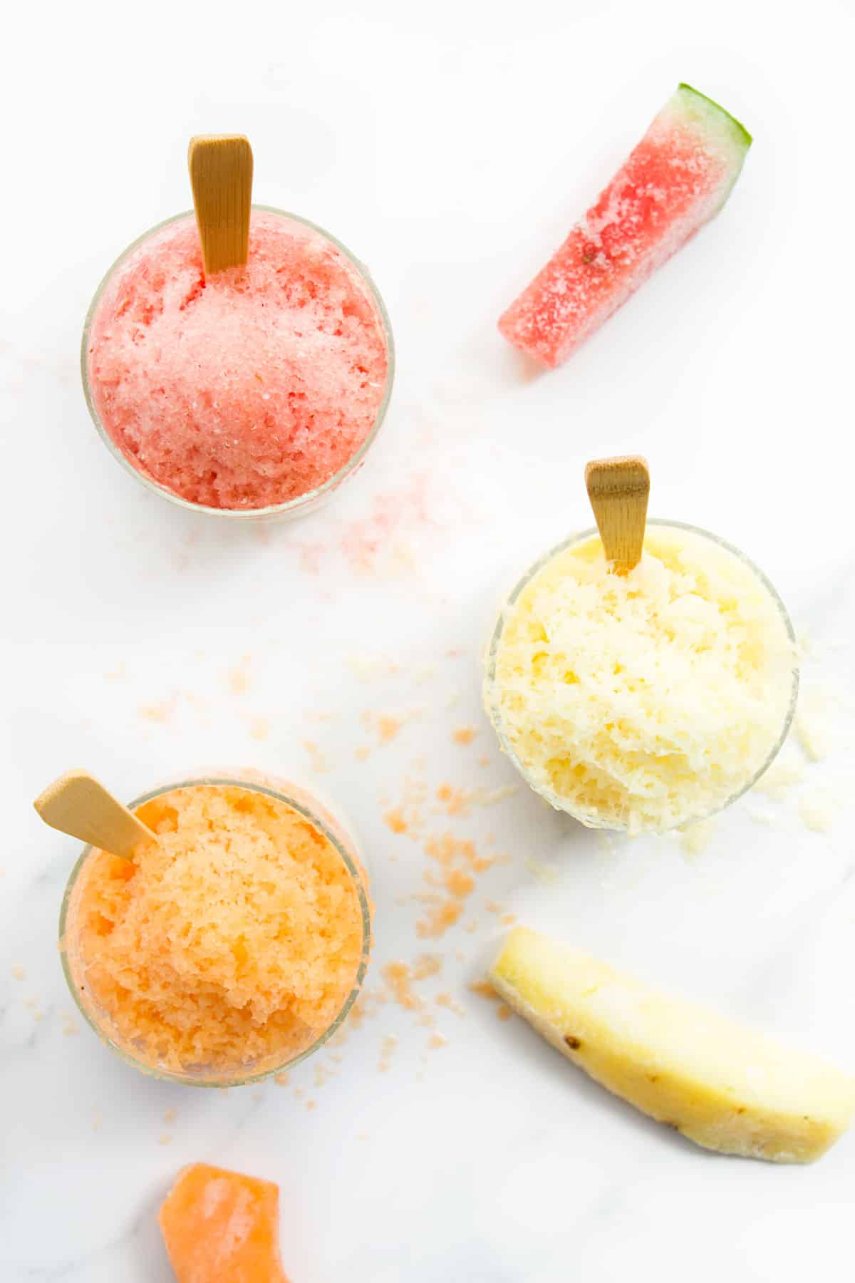 Top Down View of Frozen Fruit Shaved Ice in Glass Jars With Frozen Fruit in Background. 