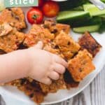 Child's hand grabbing a piece of Veggie Lentil Slice form Plate. Text Overlay "Veggie Lentil Bake"