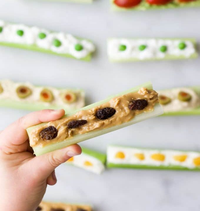 Child Holding Peanut Butter and Raisin Ants on a Log