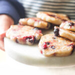 Child Holding Plate of Banana Blueberry Fritters.