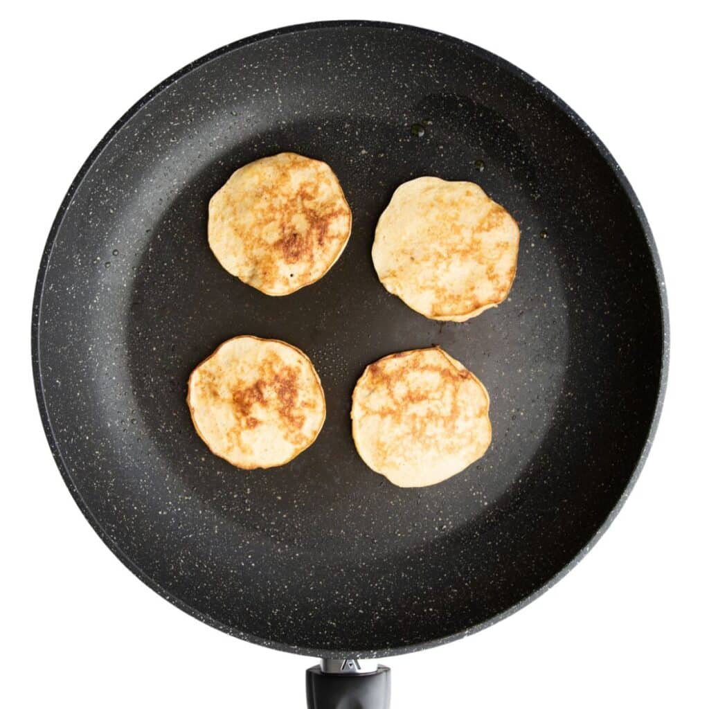 Baby Banana Pancakes In Skillet Flipped.