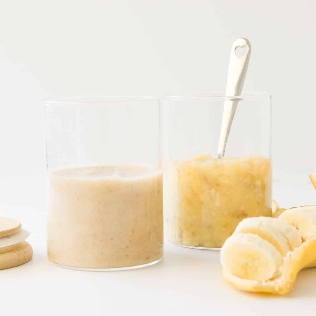 Mashed Banana and Banana Puree in Glass Jars with Slices Banana in Foreground.