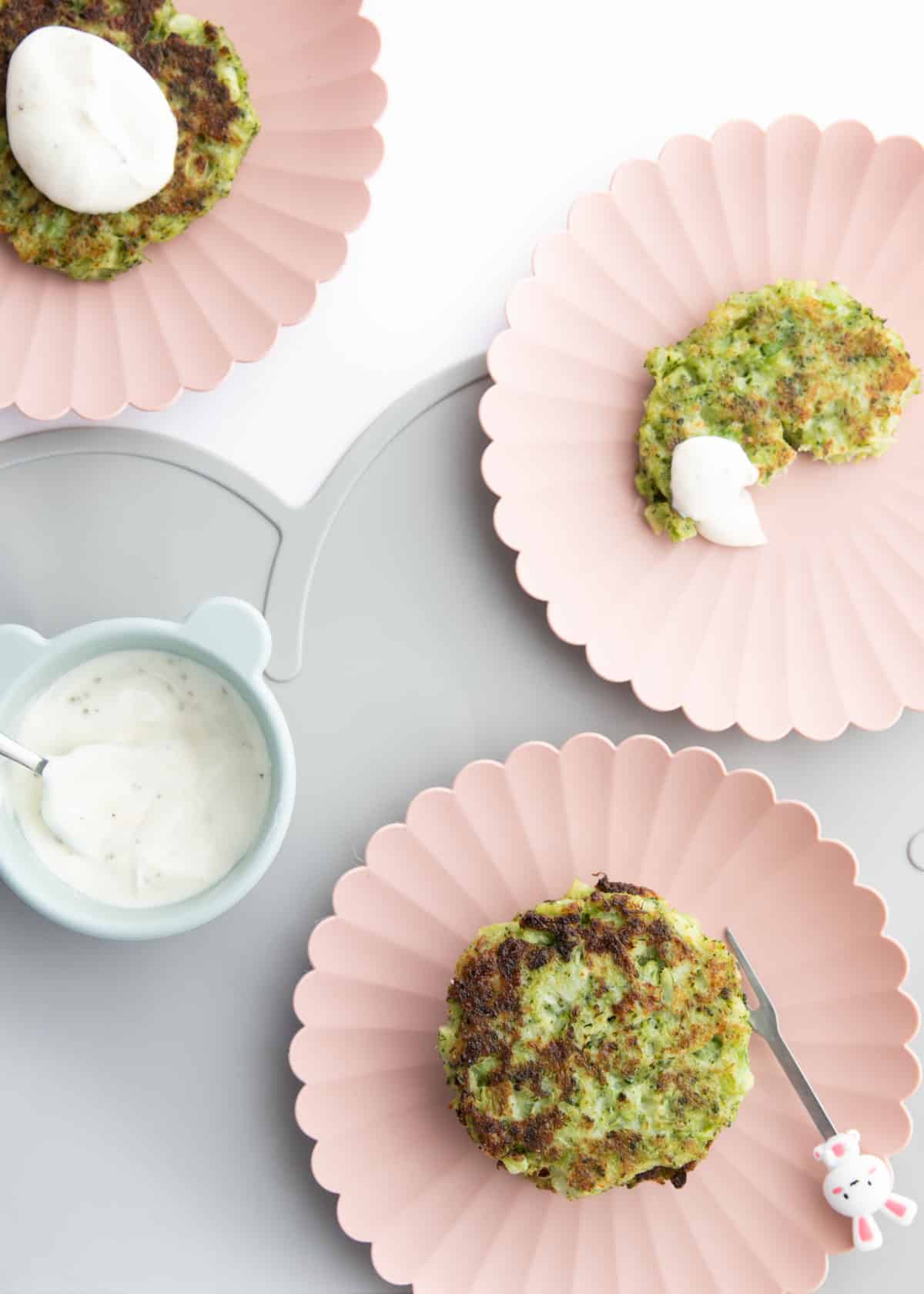 Top Down View of Broccoli Fritters on Kids Plates with a Bowl Of Yogurt Dip.