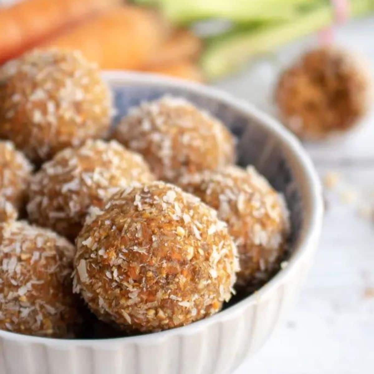 Carrot Cake Bliss Balls in White Bowl WIth Ingredients in Background. 