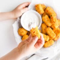 Child Holding a Cauliflower Tot Dipped in Lemon Yogurt