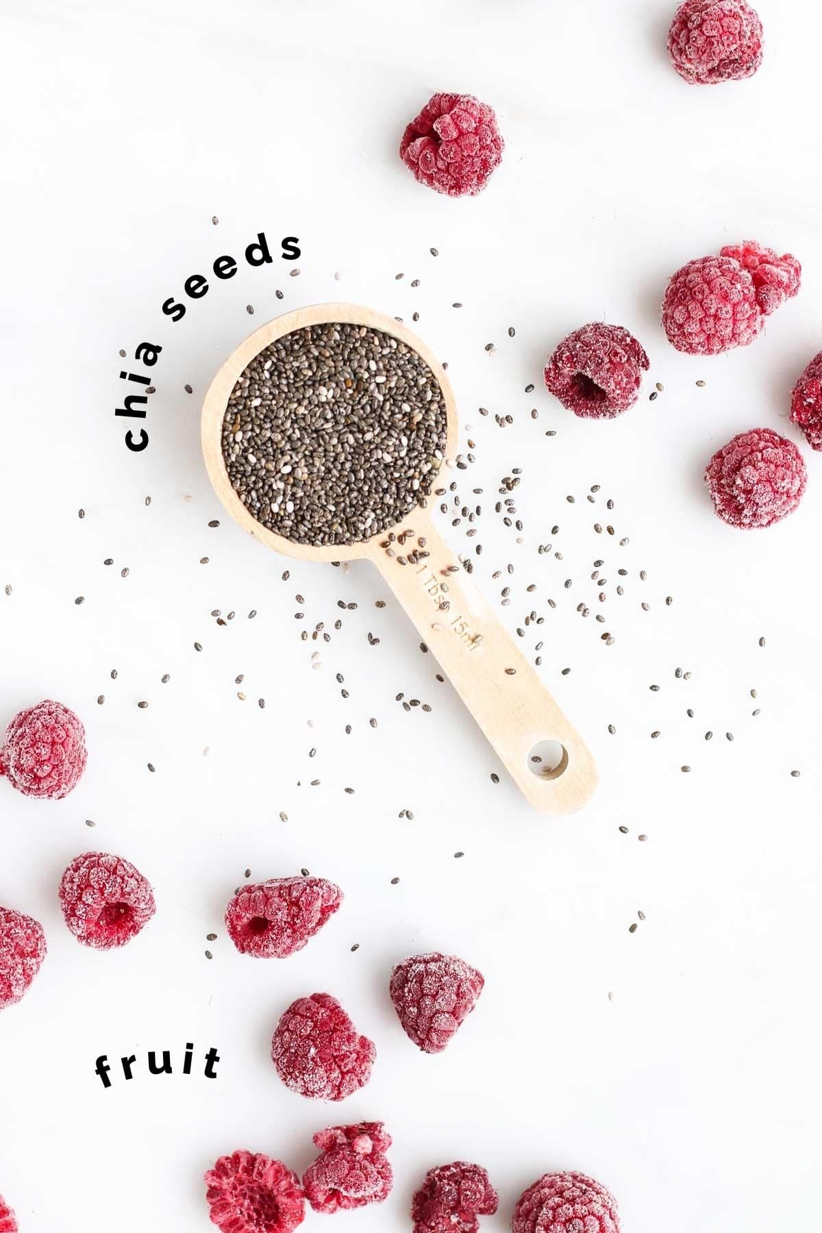 Top Down View of a tablespoon of Chia Seeds and Frozen Raspberries Scattered