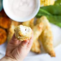 Child Holding Chicken Coconut Tender with Bite Out to Camera