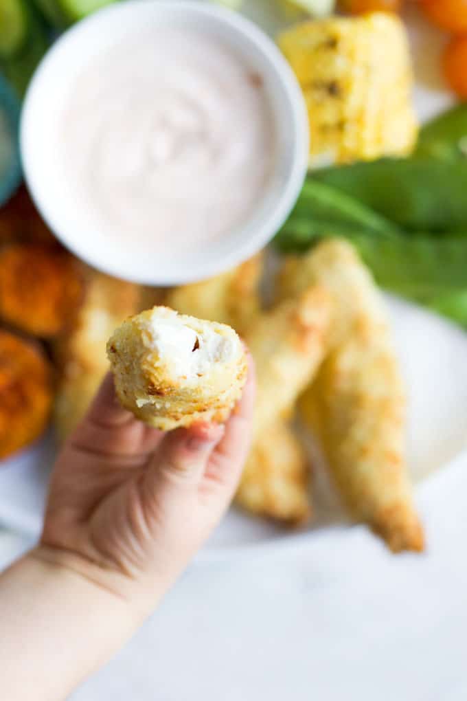 Child Holding Chicken Coconut Tender with Bite Out to Camera