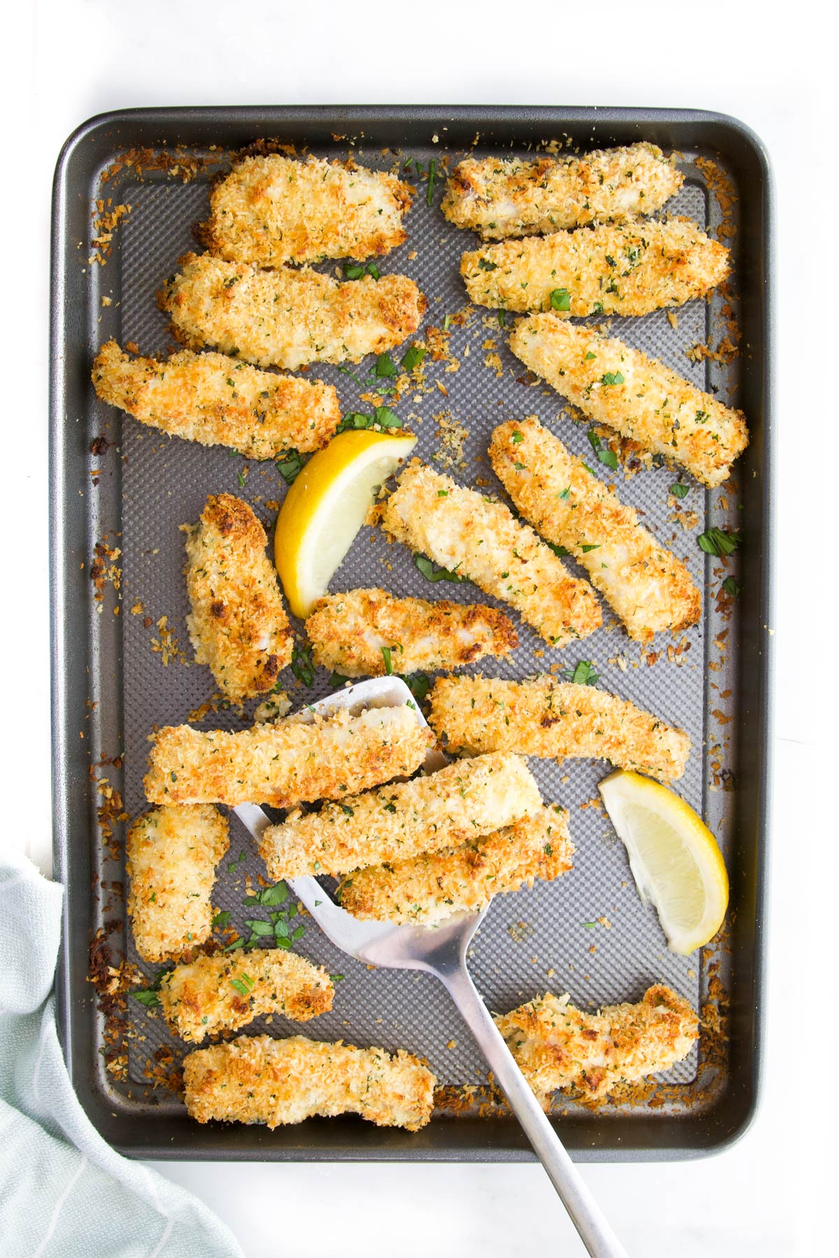 Cooked Fish Goujons  on Baking Tray with Lemon Wedges