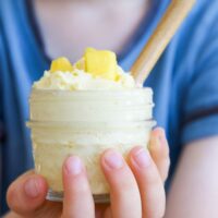 Child Holding Mango Frozen Yogurt in Glass Jar