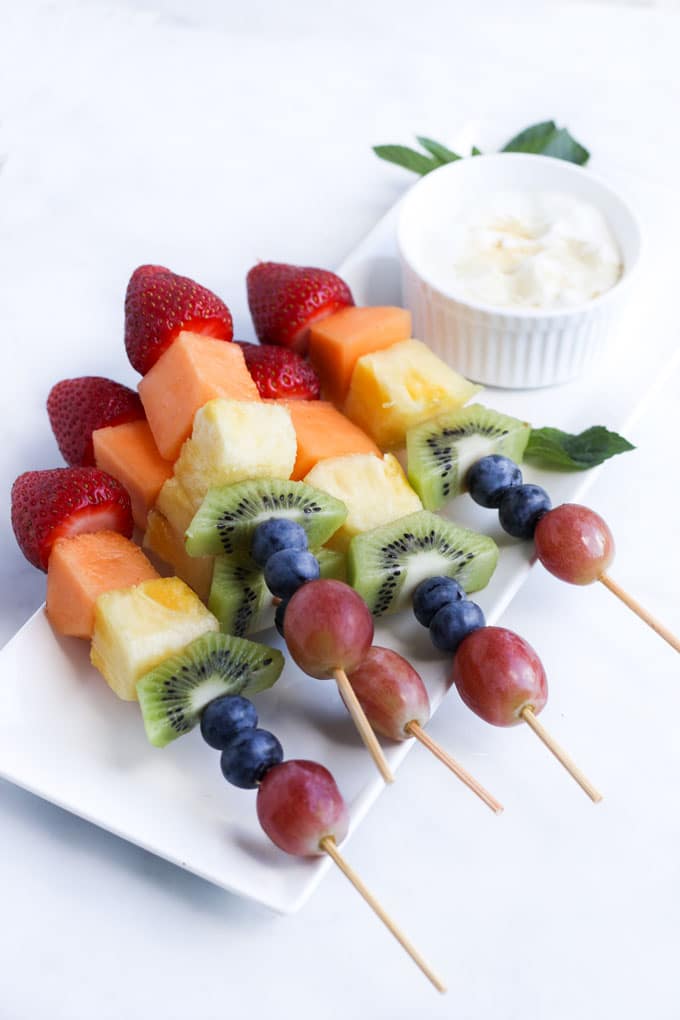 Fruit Kebabs Stacked Next to Vanilla Dip