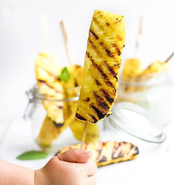 Child Holding Grilled Pineapple Spear on a Stick