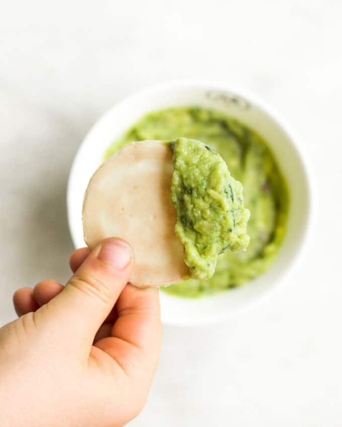 Child Holding Cracker Dipped in Guacamole