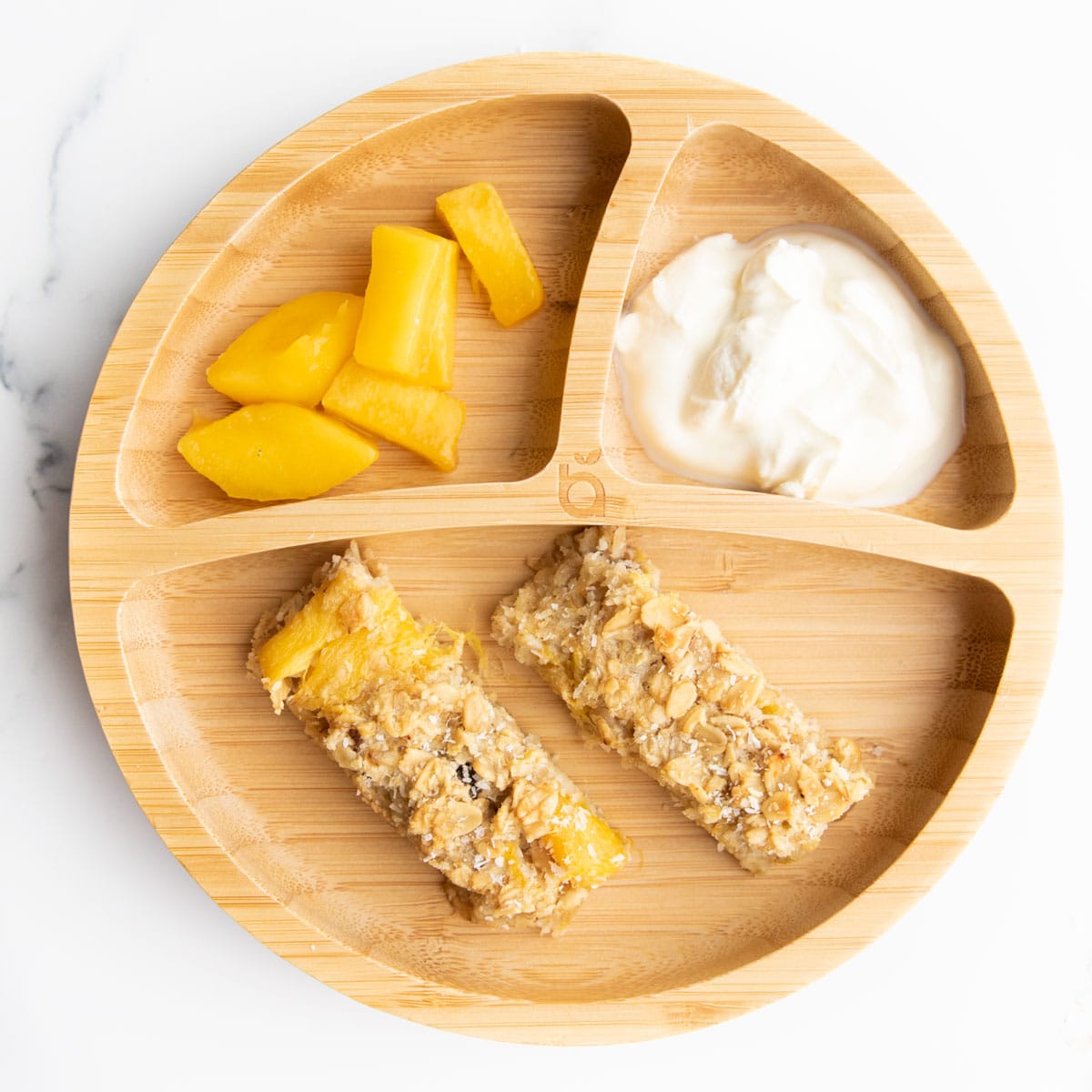 Baked Mango Oats Cut into Fingers Served on Baby Plate with Yogurt and Fresh Mango.