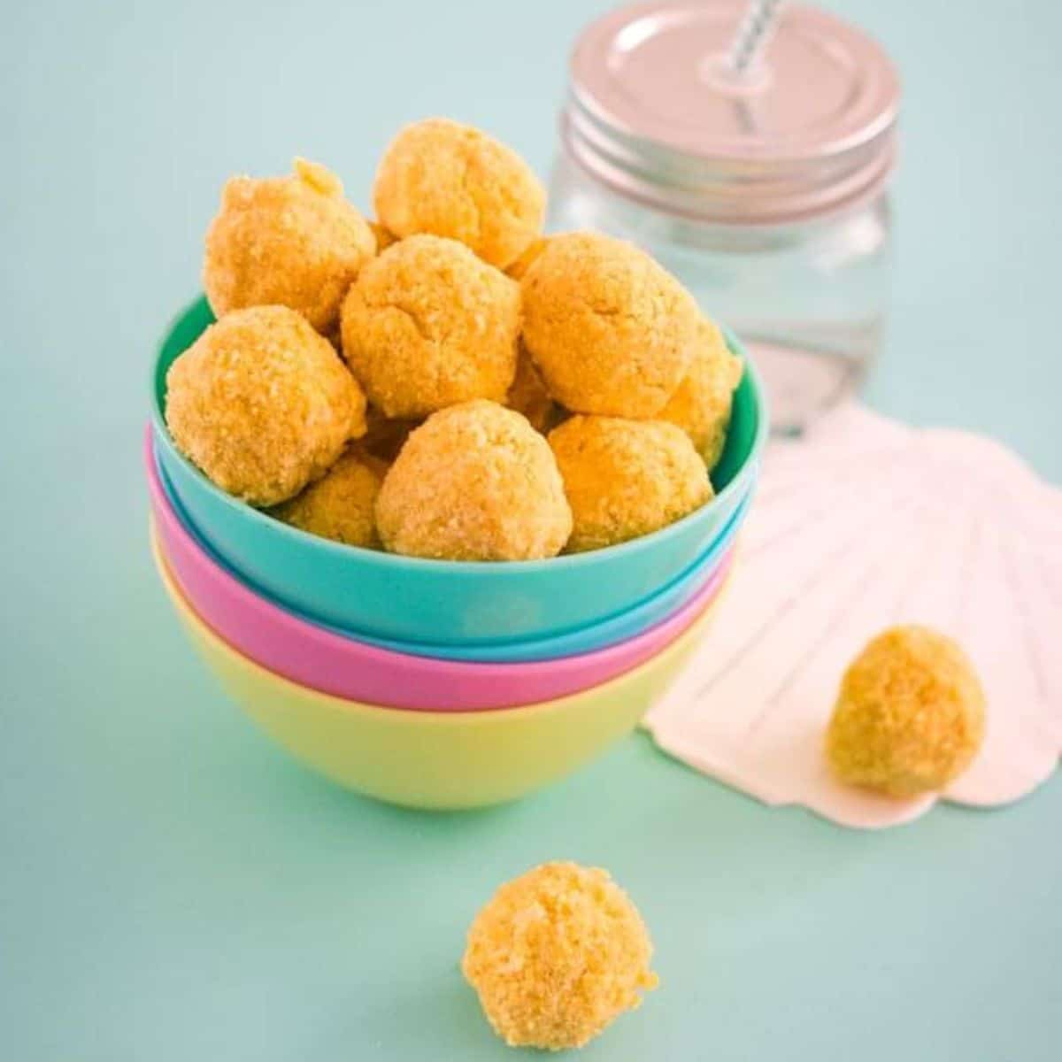 Passion Fruit Balls Sitting in Stack of Colourful Bowls with Shell and Glass Jar in Background. 