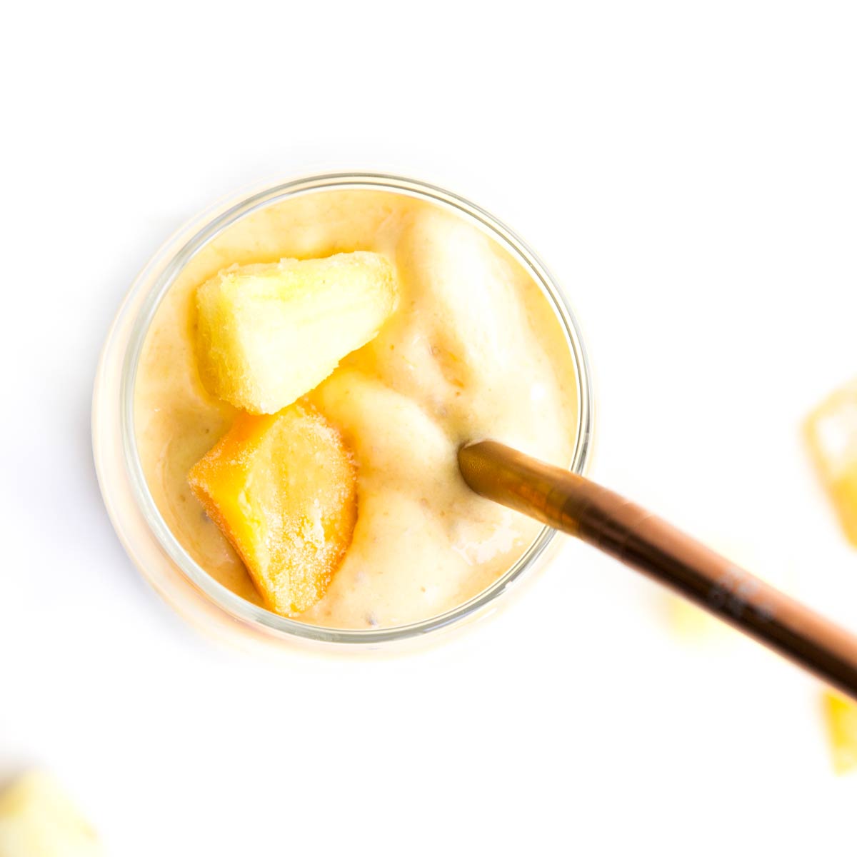 Top Down View of Mango and Pineapple Smoothie in Glass with Bronze Straw