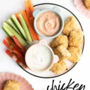 Pinterest Pin Showing Image of Quinoa Chicken Nuggets on Plate with Chopped Veggies and Dips.