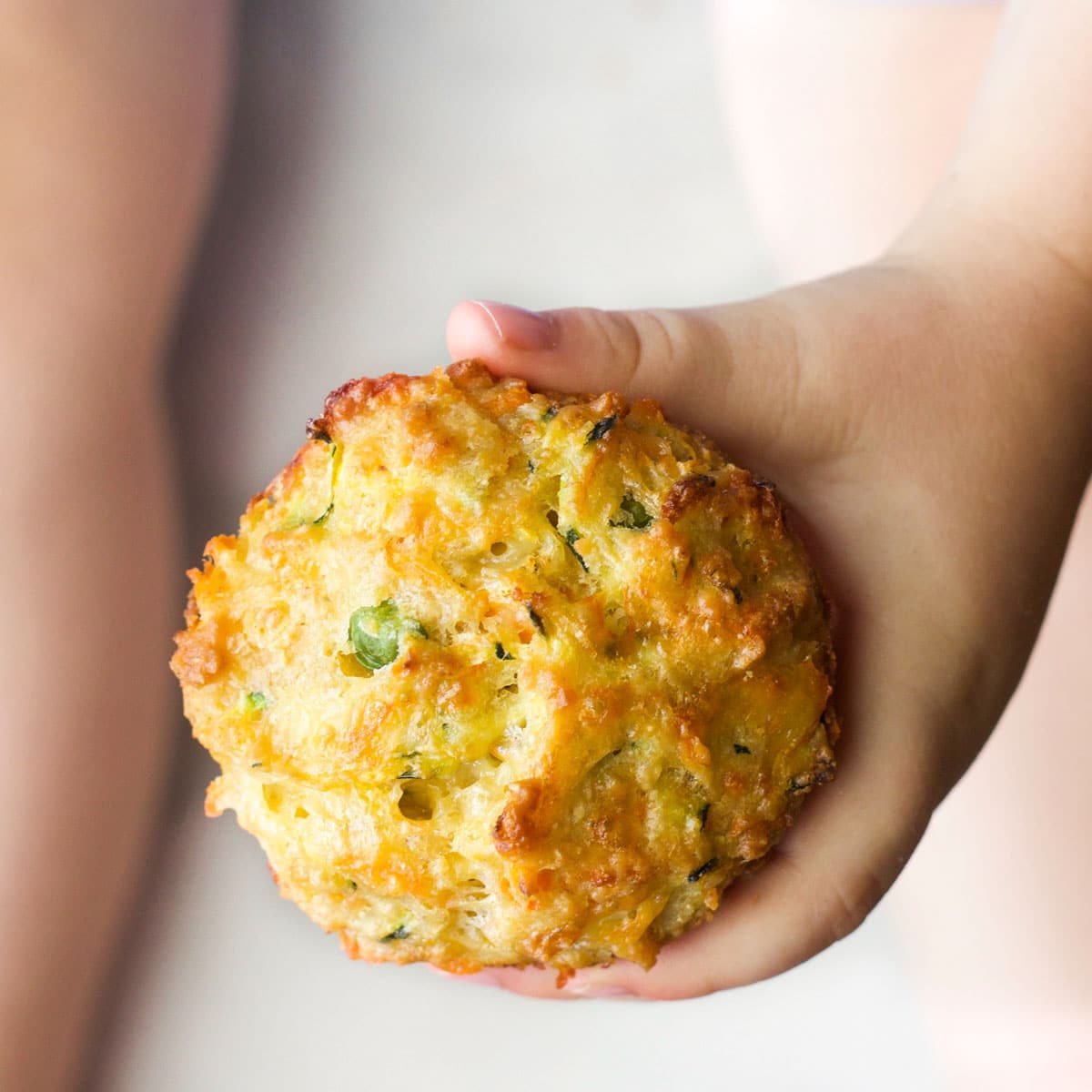 Top Down Shot of Child's Hand Holding a Savoury Muffin.