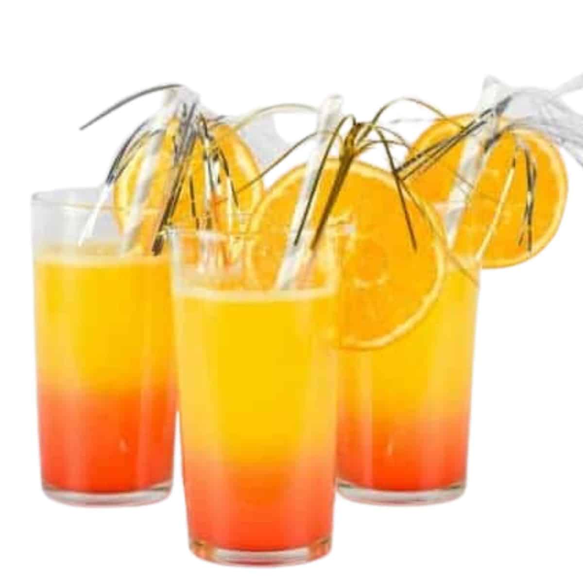 3 Gasses of Sunrise Mocktail With Slices of Oranges and Sparkler Stirrers.