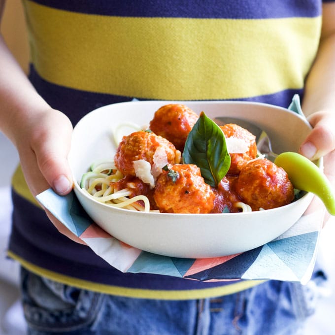 Child Holding Bowl of Turkey Meatballs in Tomato Sauce.