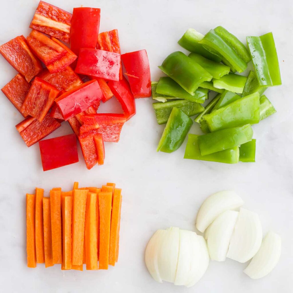 Top Down View of Red and Green Pepper Cut in Chunks, Carrots Cut into Stick and Onion Cut into Wedges